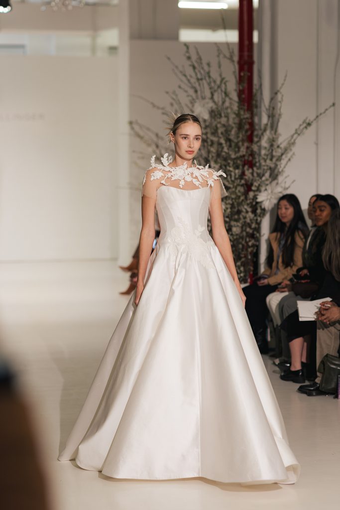 Model in white floral bridal gown on runway.