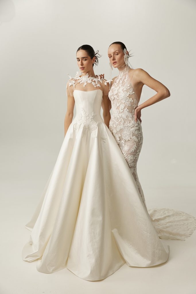 Two women in white gowns posing together.